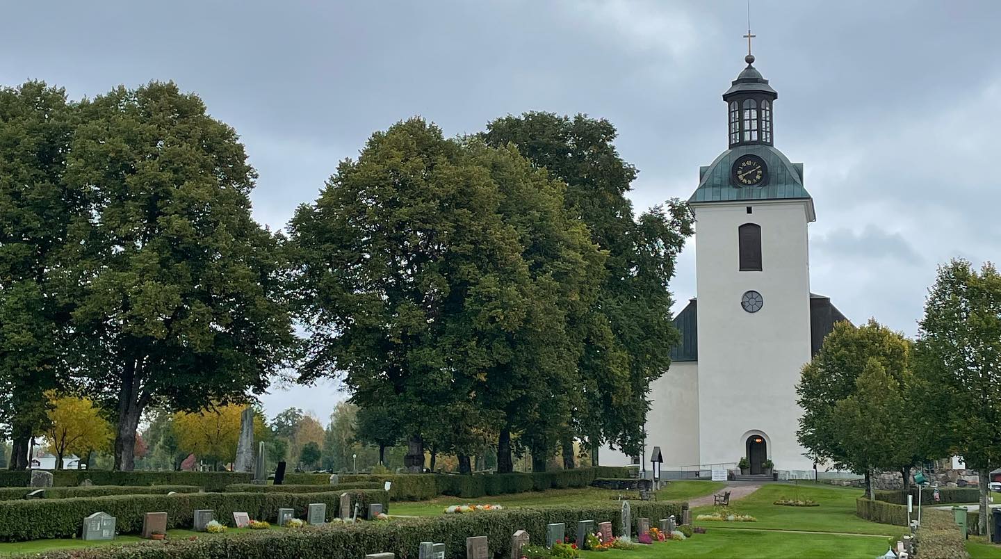 Gagnefs vita kyrka med torn och träd runt kyrkogården